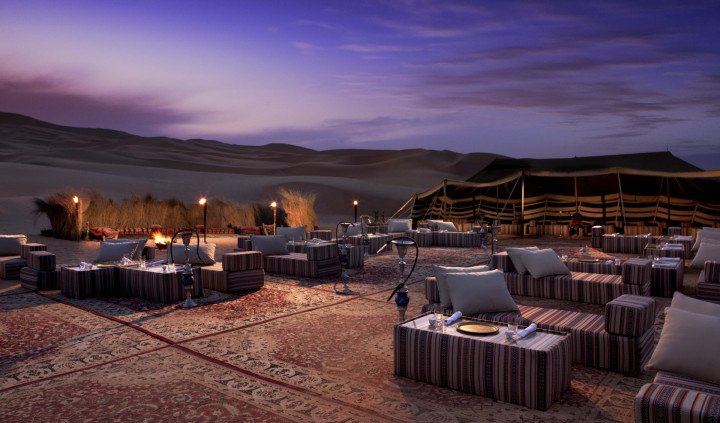 Majlis seating and lanterns at a desert camp at dusk