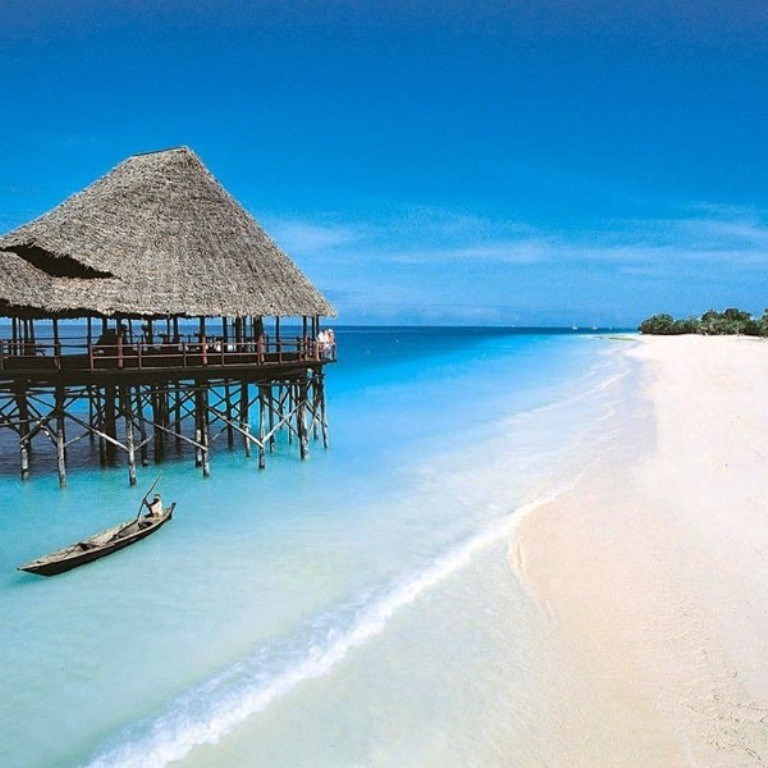A stilted thatched-roof pier restaurant over turquoise water on Watamu Beach