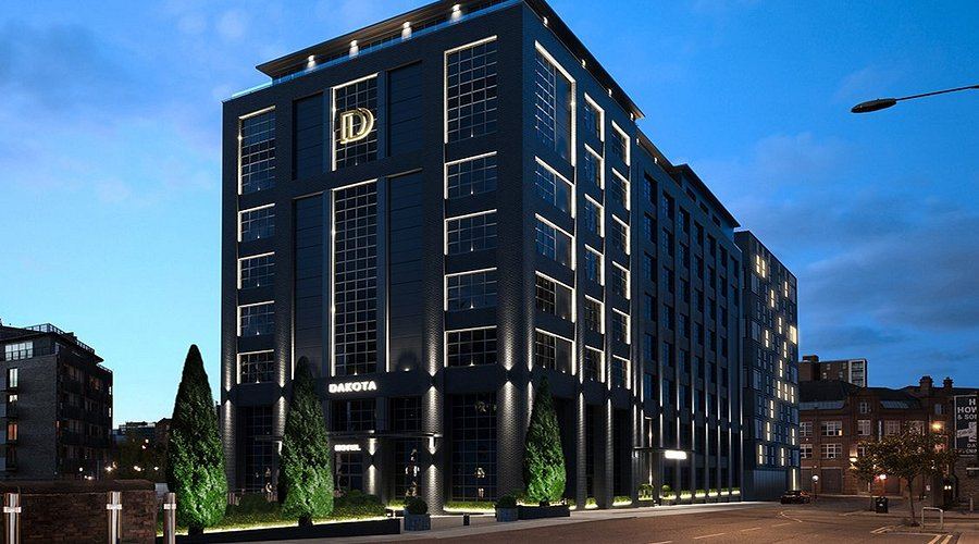 The Dakota Hotel's dark glass exterior lit up at dusk